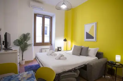 a bedroom with a large bed and a yellow wall at Monti Colosseum in Rome