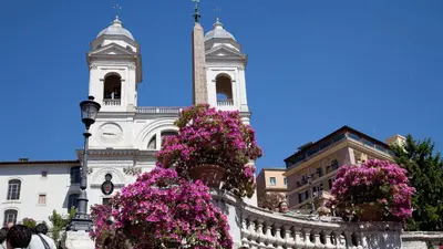 a building with a clock tower with flowers in front of it at Rental in Rome Celeste Apartment in Rome