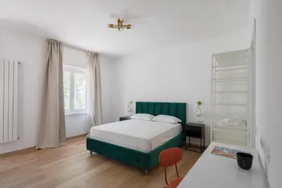a white bedroom with a bed and a red chair at Gianicolense 22 in Rome