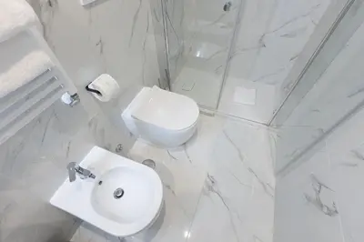 a white bathroom with a toilet and a sink at La Dolce Vita Boutique Guest House in Rome