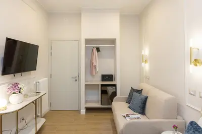 a white living room with a couch and a tv at La Dolce Vita Boutique Guest House in Rome