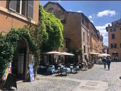 a street with people sitting at tables and umbrellas at Intimo ed Eclettico Studio a Trastevere in Rome