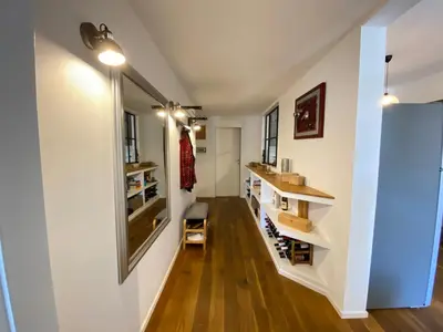 a room with white walls and wooden floors and a hallway with wine shelves at Leopardi Sweet Home in Rome
