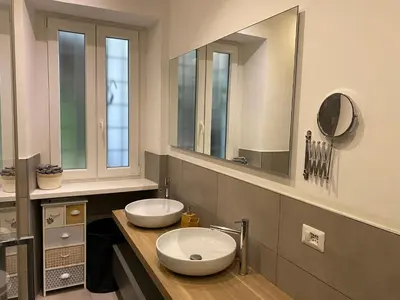 a bathroom with two sinks and two mirrors at Leopardi Sweet Home in Rome