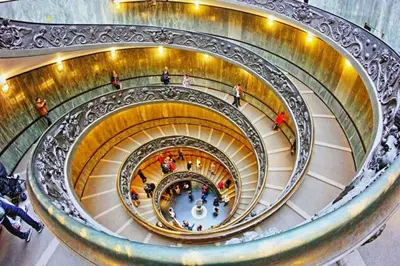 a spiral staircase in a building with people walking down it at “Suite Home Vaticano City” in Rome