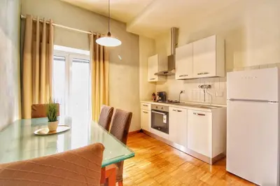 a kitchen with a table and a white refrigerator at Paglia45 Apartment at Trastevere by Yourhost in Rome
