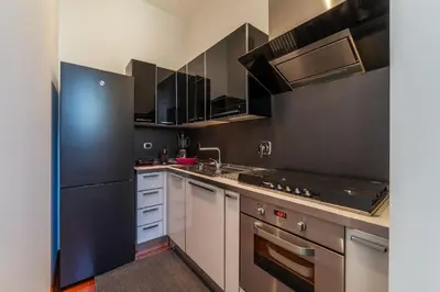 a kitchen with white cabinets and black appliances at GuestHost - Vittorio Emanuele Elegant Apartment in Rome