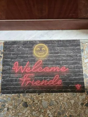 a sign that says welcome friends on a brick wall at Malatesta House in Rome