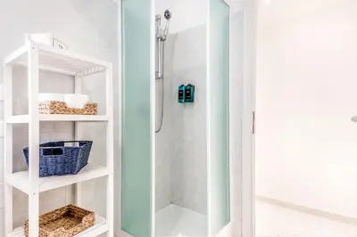 a bathroom with a shower and a white shelf at Petite Maison 19 in Rome
