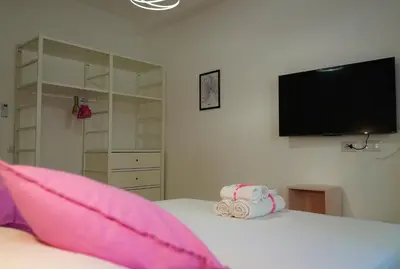 a bedroom with a bed with pink pillows and a flat screen tv at Santo Apartment in Trastevere in Rome