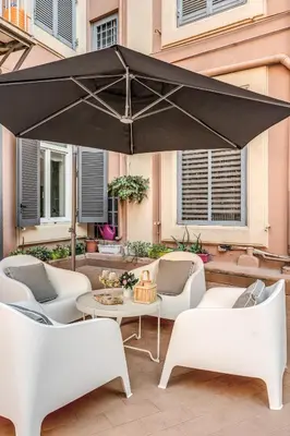 a black umbrella on a patio with chairs and a table at Daag Corso Luxury Apartment in Rome
