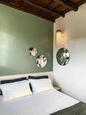 a bedroom with a white bed with four mirrors on the wall at DomusLu' - Casa di charme nel cuore di Roma in Rome
