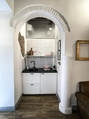 an arched kitchen with white cabinets and a sink at DomusLu' - Casa di charme nel cuore di Roma in Rome