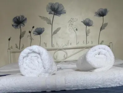 a pair of towels on a bed with flowers on the wall at Appartamento per chi ama gustare il caffè in terrazzo in Rome