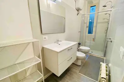 a white bathroom with a sink and a toilet at Mamisà Rome, appartamento con parcheggio privato e gratuito in Rome
