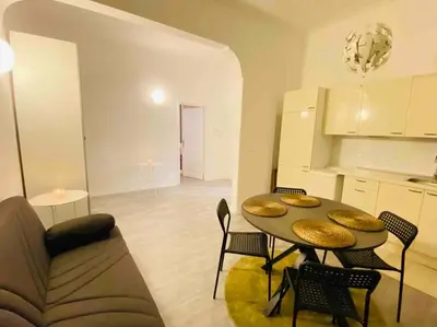 a living room with a table and chairs and a kitchen at Mamisà Rome, appartamento con parcheggio privato e gratuito in Rome