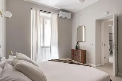 a white bedroom with a large bed and a mirror at The Best Rent - Bright flat near San Pietro in Rome