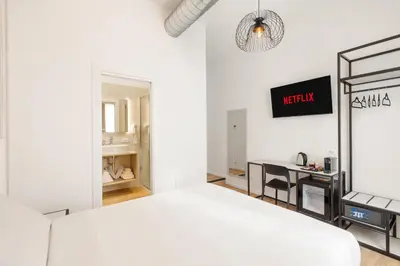 a white bedroom with a bed and a desk at Adelante rooms Piazza Bologna in Rome