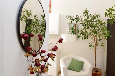 a mirror in a living room with a white chair and flowers at NuvolHouse in Rome