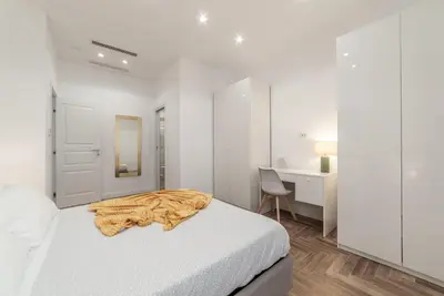 a white bedroom with a bed and a desk at Private apartment in Rome