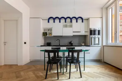 a kitchen with white cabinets and a table with stools at ROMAC Trinity with steam bath in Rome
