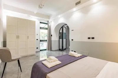a white bedroom with a bed and a chair at Laurina deluxe apartment in Rome