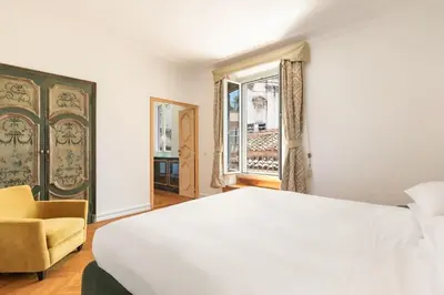 a bedroom with a white bed and a chair and a window at Casa Colonna, a Burghesius home in Rome