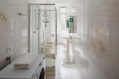 a white bathroom with a shower and a washing machine at Luminoso vicino Piazzale Flaminio e Roma centro in Rome