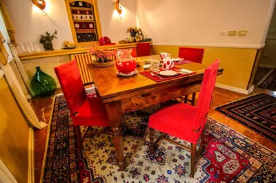 a dining room table with red chairs on a rug at Aldebaran in Rome