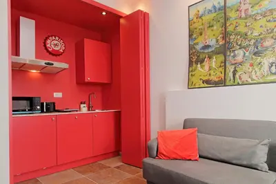 a red living room with a couch and a kitchen at suity I monkeys apartment in Rome