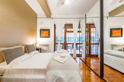 a bedroom with a white bed and a large window at Alle Mura Aurelie Apartment in Rome