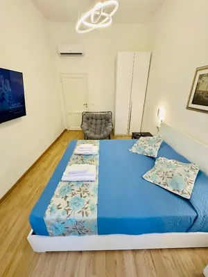 a bedroom with a bed with blue sheets and a chair at Casa Vacanza Kambal in Rome