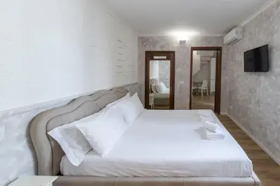 a bedroom with a white bed and a tv on the wall at Domus Augustea - 2 Floor in Rome