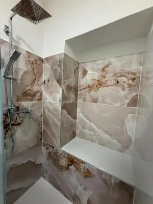 a shower in a bathroom with a marble wall at sweety rome in Rome