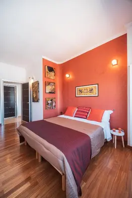 a bedroom with a large bed with an orange wall at Tiber House 60 Rome Marconi - Rome Vacation M&D in Rome
