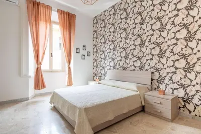 a bedroom with a bed with a floral accent wall at San Lorenzo Residence two in Rome