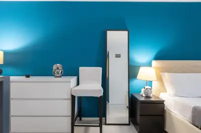 a blue bedroom with a white chair and a bed at Lovely Cozy Apartment Parioli in Rome