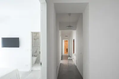 a hallway in a white house with a hallway leading to a bathroom at Claudio Vaticano Home in Rome