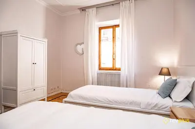a white bedroom with two beds and a window at Mecenate Apartment Fori Imperiali in Rome