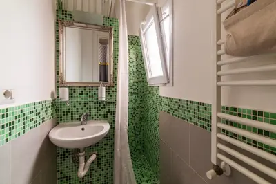 a green tiled bathroom with a sink and a mirror at GuestHost - San Lorenzo Welcoming Apartment in Rome