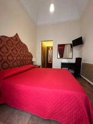 a bedroom with a large red bed with a desk at Alloggio Turistico in Rome