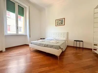 a white bedroom with a bed and a wooden floor at Montezebio Boutique Apartment in Rome