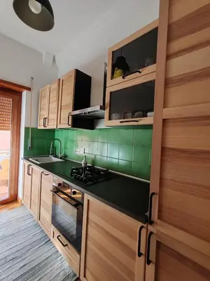 a kitchen with green tiled walls and wooden cabinets at Domus Cornelia in Rome