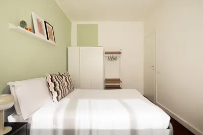 a bedroom with a white bed and a white cabinet at Domiziano Boutique Apartment in Rome