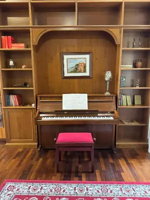 a piano with a red stool in a room with shelves at Colosseum's Custodian - Apartment 115 m2 in Rome