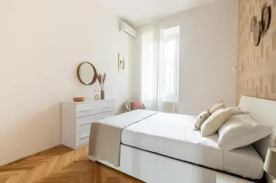 a white bedroom with a bed and a dresser at Charming Vatican Apartment in Rome