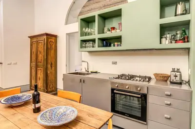 a kitchen with a wooden table with a bottle of wine at Trastevere 2 bdr orto botanico with private patio in Rome