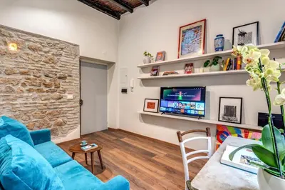 a living room with a blue couch and a tv at Vicolo leopardo suite Trastevere in Rome