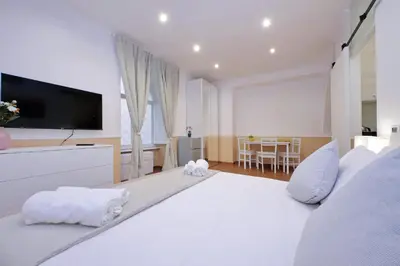 a large white bedroom with a large bed with a flat screen tv at Trevi Feddy's Apartment in Rome