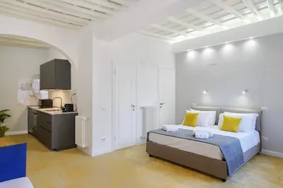 a white bedroom with a bed and a kitchen at Monserrato Charme Apartment - Campo dei Fiori in Rome